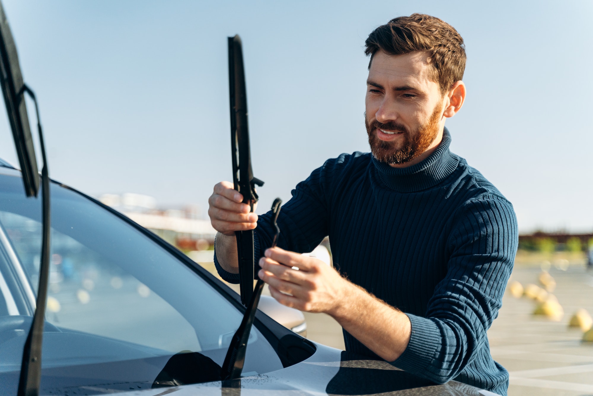 Male auto owner checking windshield wiper at the street. Male auto owner checking windshield wiper at the street.